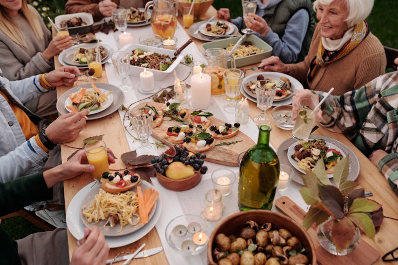 Repas convivial préparé par un traiteur avec des plats variés, servi à table pour une réunion de famille en plein air